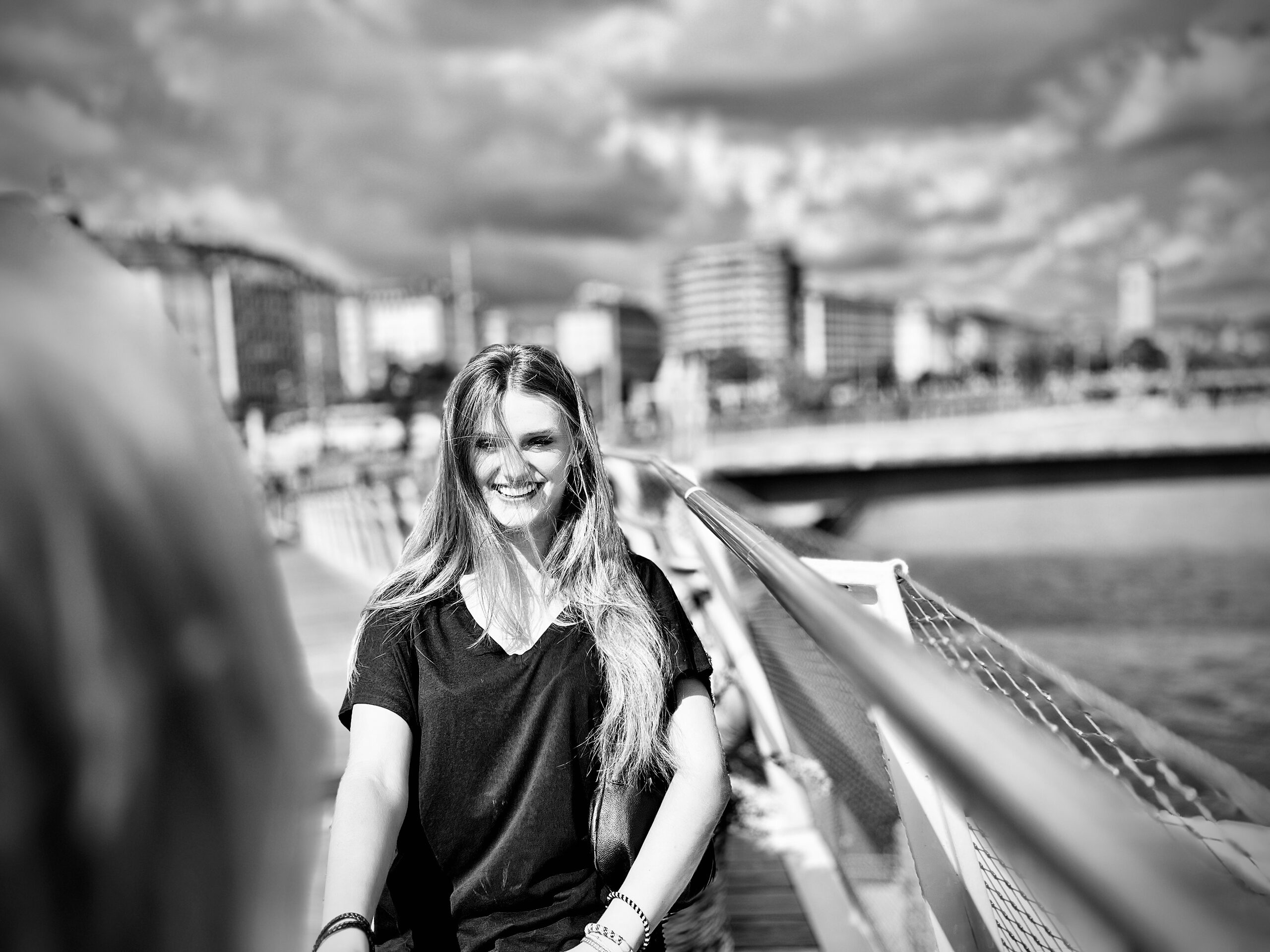 Eine Frau am Geländer der Brücke, dahinter der Donaukanal und die Häuser am Ufer.